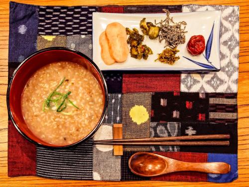 a bowl of soup on a table with a plate of food at Guest House Takazuri-KITA in Nanto