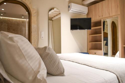 a hotel room with a bed and a tv at Philikon Luxury Suites in Rethymno Town