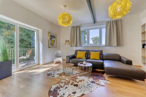 德拉塞斯里德的住宿－Das Bachhaus，客厅配有黑色真皮沙发和黄色枕头。