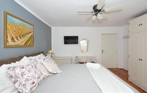 a bedroom with a white bed with a ceiling fan at Bora bora Apartment in Kaštela