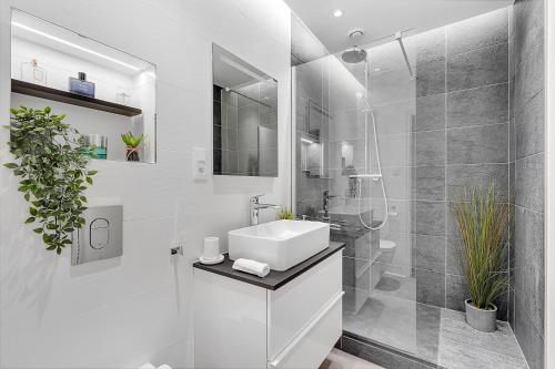 une salle de bain blanche avec un lavabo et une douche dans l'établissement LE CODRUS - Charmant appartement dans l'hyper centre toulousain, à Toulouse
