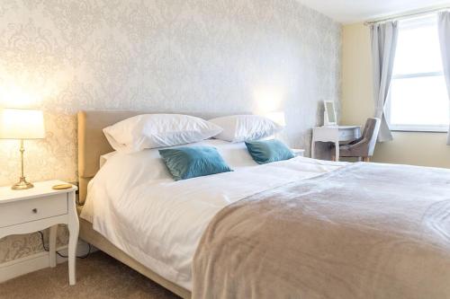 a bedroom with a white bed with two blue pillows at Cosy, Boutique Central Kirkby Lonsdale Apartment in Kirkby Lonsdale