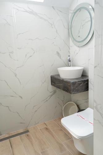 a white bathroom with a sink and a toilet at Dion Apartments in Lozenets