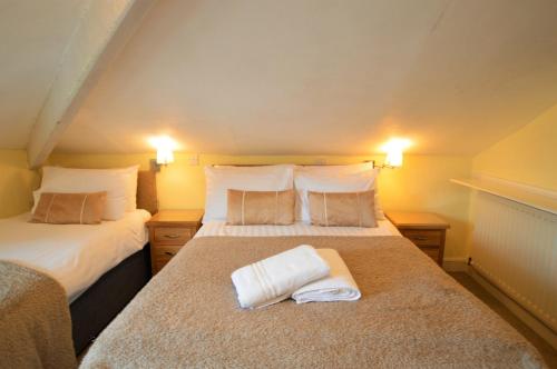 a bedroom with two beds with towels on the bed at All Seasons Guest House in Windermere