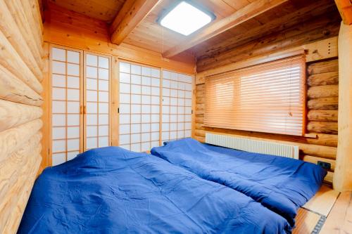 a bedroom with a blue bed in a wooden cabin at Lake Toya Hillside House in Lake Toya