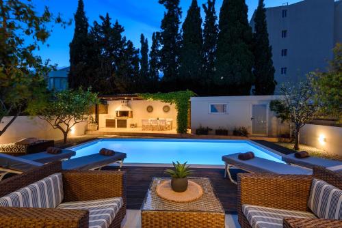 a pool in a backyard at night with wicker furniture at Vasiliki Villa in Ialysos