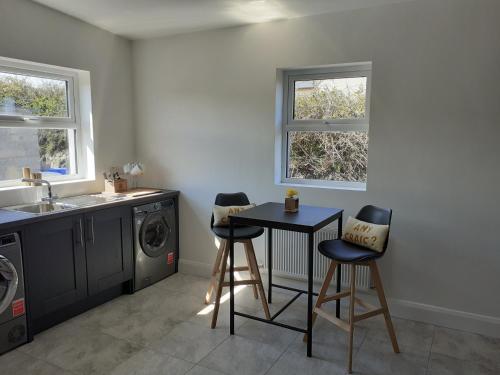 uma cozinha com uma máquina de lavar roupa, uma mesa e cadeiras em An Sean Teach em Fodry