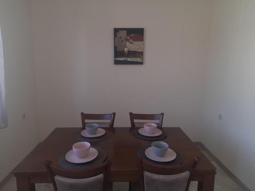 a wooden table with chairs and cups and plates on it at Sandanski city center apartment in Sandanski