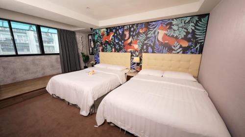 two beds in a room with a painting on the wall at Urtrip Hotel in Taipei