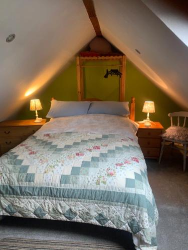 リドフォードにあるHeathergate Cottage Dartmoor BnBのベッドルーム1室(大型ベッド1台、テーブル上のランプ2つ付)