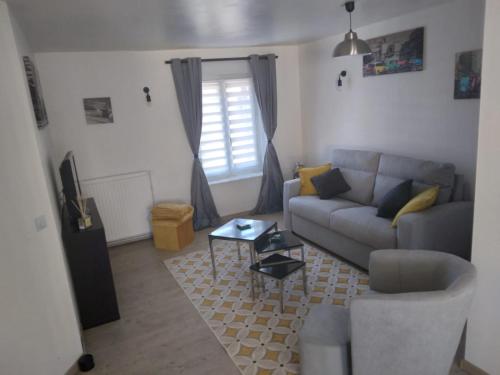 ein Wohnzimmer mit einem Sofa und einem Tisch in der Unterkunft Bel Appartement lumineux avec extérieur in Rosières-aux-Salines