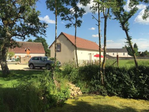 ein Auto, das vor einem Haus mit einem roten Regenschirm parkt in der Unterkunft La cabane de la mare - Meublé de tourisme 3 étoiles in Précy