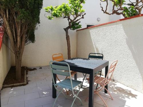 une table et des chaises assises sur une terrasse dans l'établissement Les Marines II - New Design - En bord de mer - Tout Confort - Proche commerces et Animations, au Barcarès