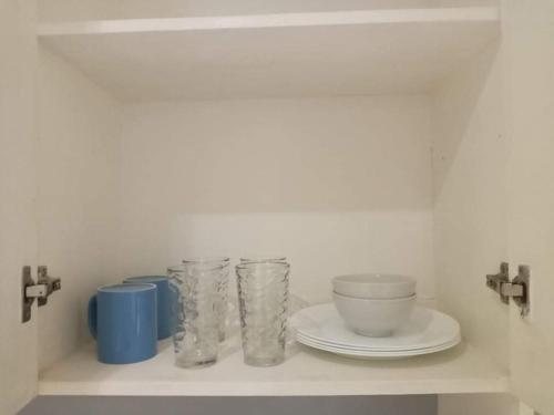 a shelf with cups and plates on it at LIAM's Staycation in Manila