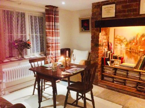 sala de estar con mesa y chimenea en Virginia Cottage, en Bulwick