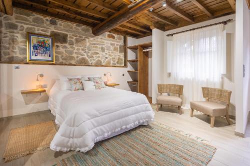 a bedroom with a large bed and a stone wall at Entre Os Ríos - Casa Rural y Enoturismo in A Pobra do Caramiñal