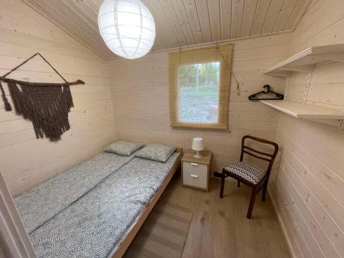 Habitación pequeña con cama y silla en Domki Letniskowe na Dzikiej en Tolkmicko