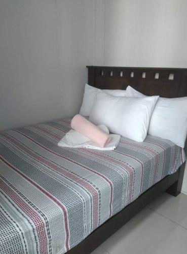 a bed with white pillows and a pink pillow on it at LIAM's Staycation in Manila