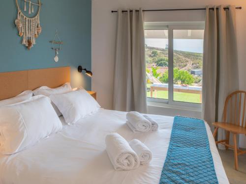 una camera da letto con un letto bianco con asciugamani sopra di Ao Sabor do Vento (+12 ) ad Aljezur
