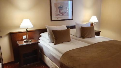 a hotel room with a bed with two lamps on it at Hotel Garden Club in Braşov