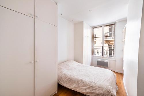 a white bedroom with a bed and a window at SAINT GERMAIN DES PRES - BAIL MOBILITE in Paris