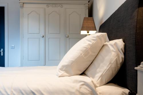 a bedroom with white pillows on a bed with a lamp at Bryan Street Apartments in Ballymena