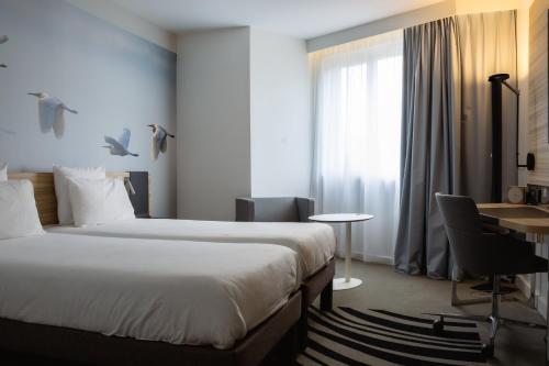 a hotel room with two beds and a desk at Novotel Valence Sud in Valence