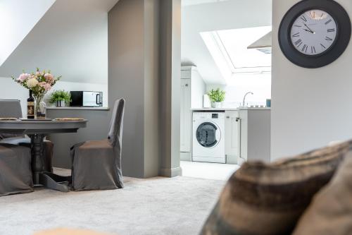 a kitchen with a table and a clock on a wall at Bryan Street Apartments in Ballymena