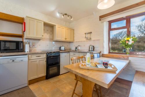 a kitchen with white appliances and a wooden table at Cargurra Farm in Boscastle