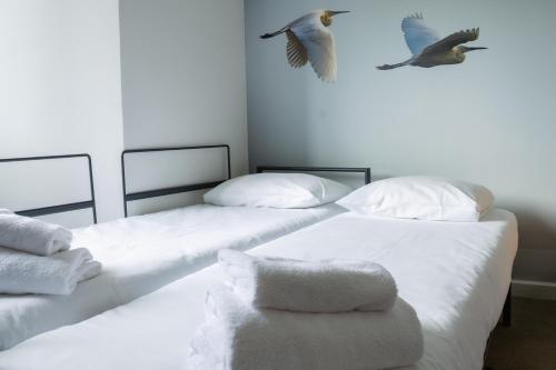 two beds with white sheets and a bird flying above them at Novotel Valence Sud in Valence