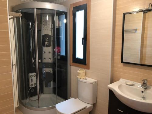 een badkamer met een douche, een toilet en een wastafel bij Apartamento para 6 personas con piscina y paddle in Foz