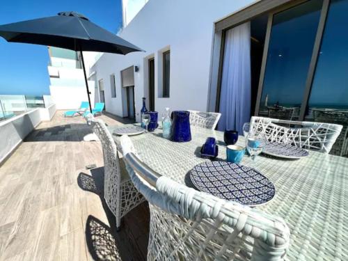 a table with chairs and an umbrella on a balcony at ANFA LIVING - LES TERRASSES D'ANFA # Front Sea VIEW 180 - 2 or 3 bedrooms in Casablanca