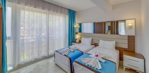 a bedroom with two beds and a large window at Marcan Resort Hotel in Oludeniz