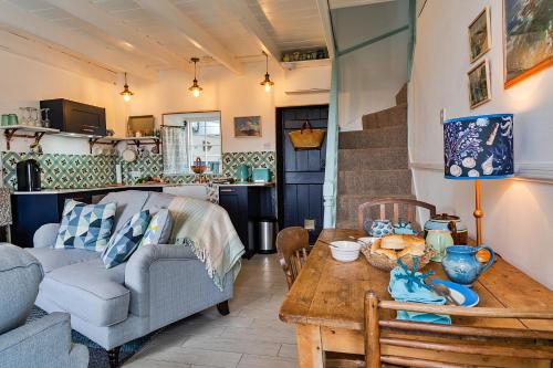 
a living room filled with furniture and a table at Cosy Mousehole Cottage With Sea Views in Mousehole

