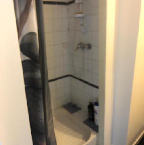 La salle de bains est pourvue d'une douche et de carrelage. dans l'établissement Le Comtois, studio au calme proche de la gare, à Besançon