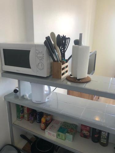 - une étagère de cuisine avec un four micro-ondes et quelques ustensiles dans l'établissement Le Comtois, studio au calme proche de la gare, à Besançon