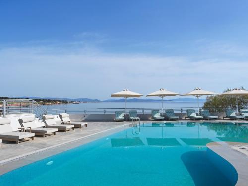 uma piscina com cadeiras e guarda-sóis em NLH Mati Seafront - Neighborhood Lifestyle Hotels em Mati