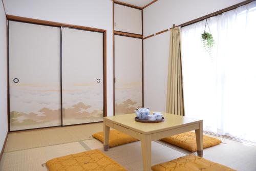 a living room with a table and large windows at Green House 101 in Tokyo