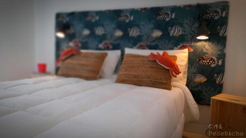 Una cama con sábanas blancas y una almohada de pescado. en São João da Caparica Beach Apartment, en Costa da Caparica