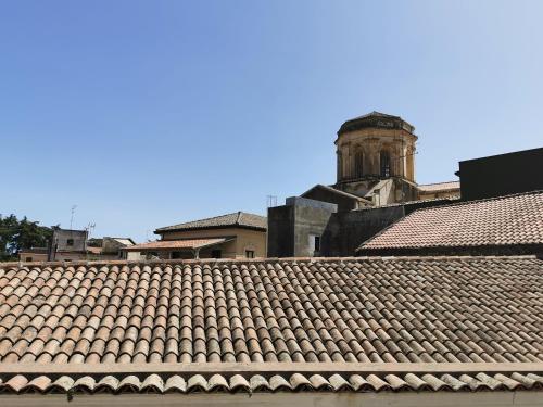 un toit en carrelage d'un bâtiment avec une tour d'horloge dans l'établissement Loft San Mauro, à Viagrande