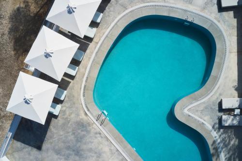 an overhead view of a swimming pool with cyan water at NLH Mati Seafront - Neighborhood Lifestyle Hotels in Mati
