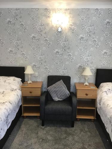 sypialnia z 2 łóżkami, krzesłem i 2 szafkami nocnymi w obiekcie The New Inn Motel w mieście York