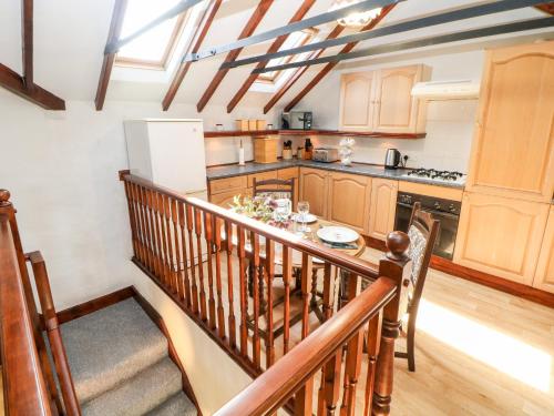 a kitchen with wooden cabinets and a staircase with a table at The Olde Coach House in Bradwell