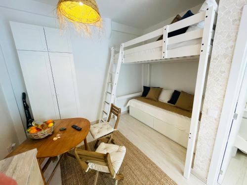 アルマカオ・デ・ペラにあるTiny Beach House Armação de Pêraのテーブルと二段ベッド付きの小さな部屋です。