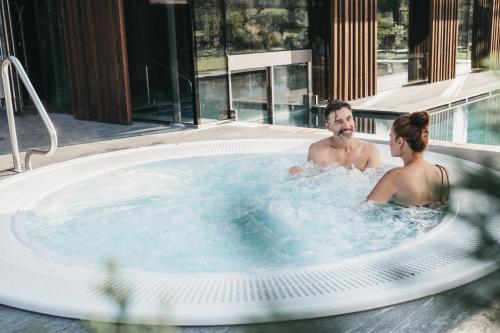 a man and a woman in a hot tub at Hotel Rudolf in Brunico