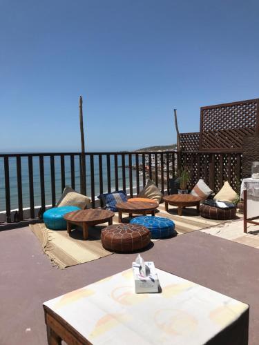 a group of tables and benches on a patio overlooking the ocean at Single fin beach house in Taghazout