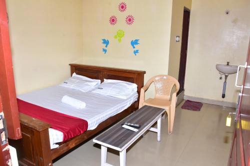 a bedroom with a bed and a chair and a sink at Sri Krishna Guest House in Pondicherry