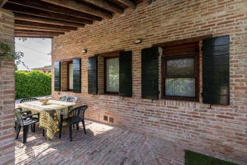 a patio with a table and chairs and a brick wall at Country house Viaro_150sqm in Vanzo