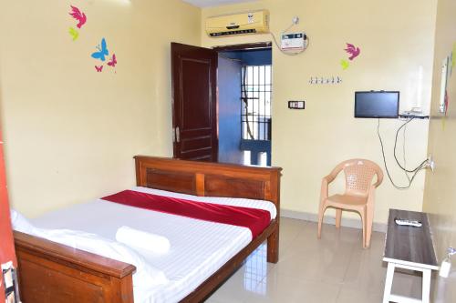 a bedroom with a bed and a table and a chair at Sri Krishna Guest House in Pondicherry