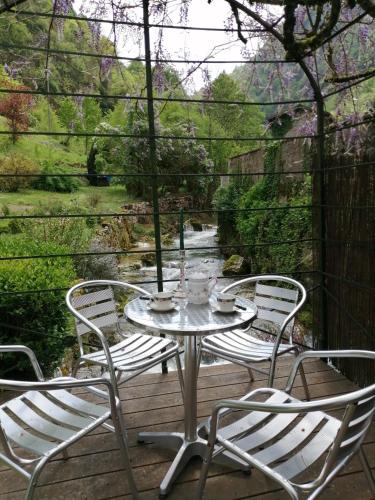 a table and chairs on a deck with a view of a river at Au fil de l'eau in Cerdon